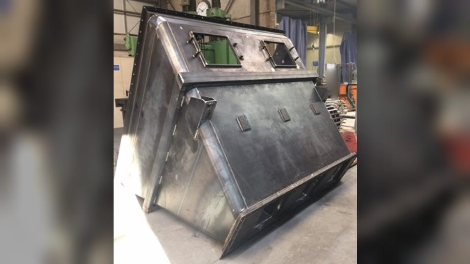 Packsilo aus Stahlblech, frisch geschweißt und liegend in der Werkstatthalle, oben mit zwei rechteckigen Öffnungen