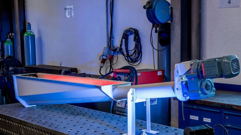 Förderschnecke mit trichterförmigem Einlauf und Getriebemotor auf einem Schweißtisch in unserer Werkstatt